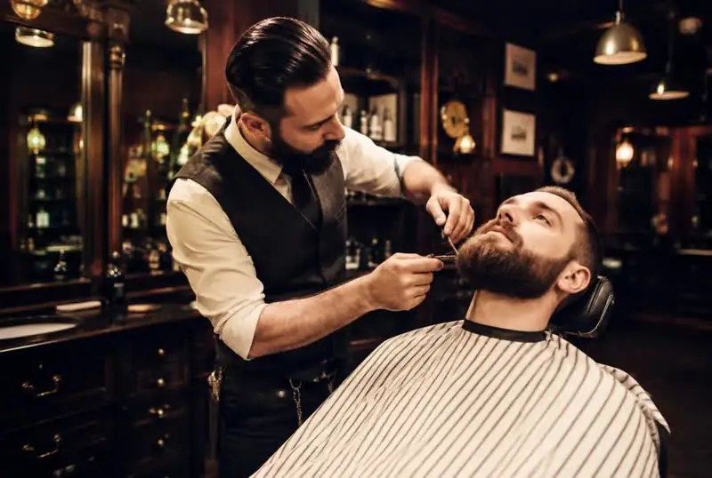 Barber trimming a client's beard in a barbershop